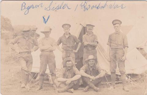 A black-and-white photograph of a group of soldiers posing in front of a tent.