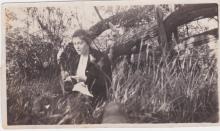 A screen grab of Mildred Sisler sitting by a wooden fence with an inset image of Byron and Mildred