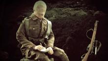 A screen shot of the mannequin-soldier sitting in the trench and writing a letter.