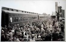 A black and white photograph of a large crowd of both soldiers and civilians at a train station