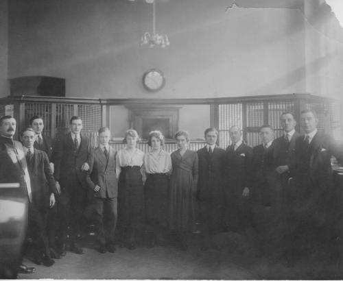 Une photographie en noir et blanc de Byron Cooper Sisler posant avec des collègues de la banque.