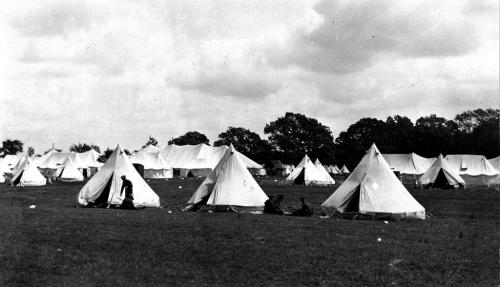 A black and white photograph of two groups of soldiers by white military tents  at Camp Niagara.