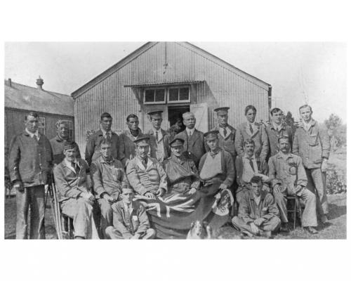 Jack Munroe and his dog sitting with a group of soldiers outside a hospital  building.