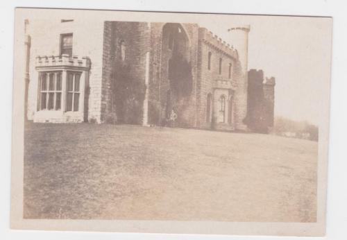 A photograph of a castle in the distance with a soldier posing in front of it.