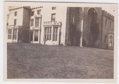 Une photographie d’un soldat posant devant de grandes fenêtres d’un château d’Angleterre.