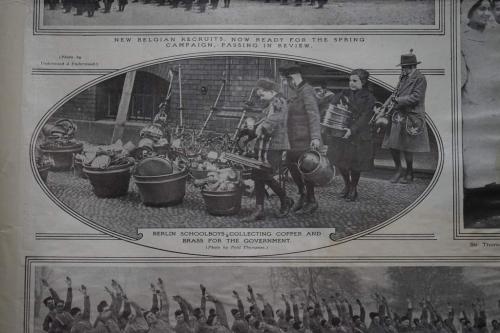 A black-and-white photograph of German children placing metal objects into containers on the street.