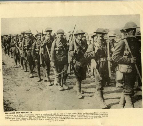 Une photographie en noir et blanc d’une longue file de soldats portant des pioches.