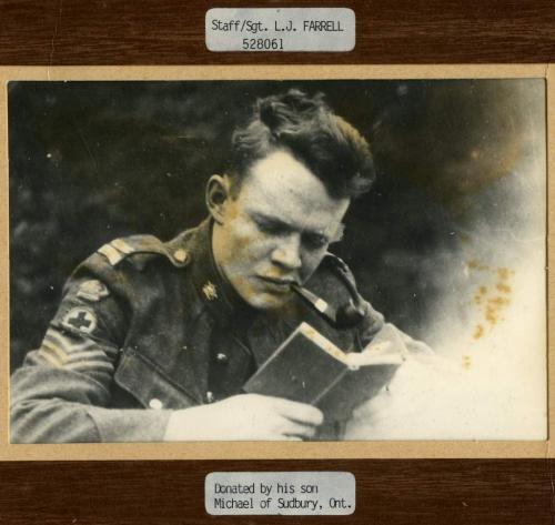 Une photographie en noir et blanc du Sergent d’état-major médical Lesile John Farrell lisant un livre.