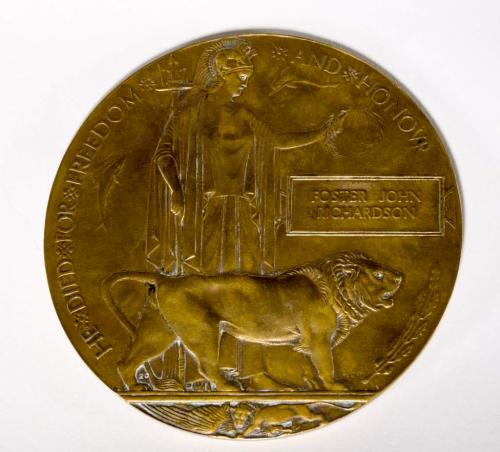 A bronzed round plaque inscribed with the words “He died for freedom and  Honour”.