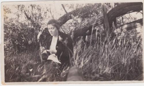 A black-and-white photograph of Mildred Sisler sitting by a wooden fence.