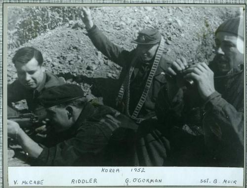 A black-and-white photograph of four soldiers in a dugout.