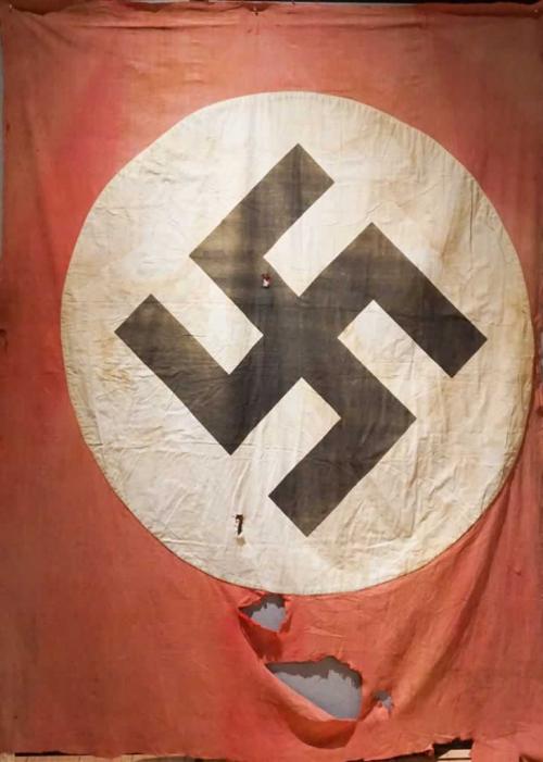Un drapeau nazi typique rouge ayant une croix gammée noire au centre d’un cercle blanc.