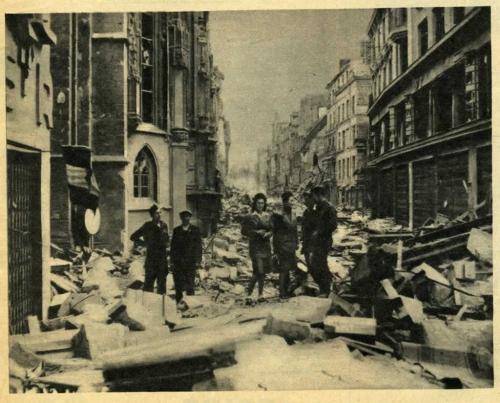 A black-and-white photograph of a civilian and several soldiers in a bombed-out city.