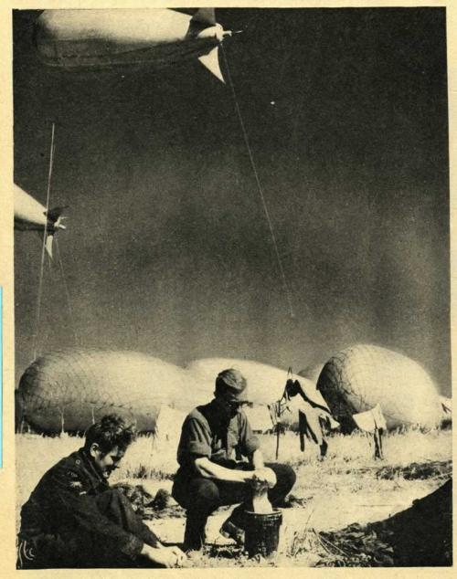 Une photographie en noir et blanc de deux soldats faisant leur lessive avec de grands ballons flottant en arrière-plan.