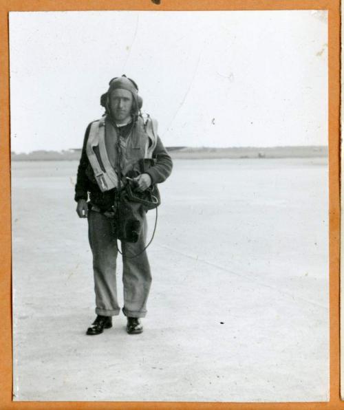 A black-and-white photograph of a soldier in Air Force uniform walking  down a street.