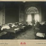 A black-and-white photograph of three soldiers in a room lined with cots.