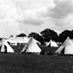 A black and white photograph of two groups of soldiers by white military tents  at Camp Niagara.