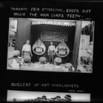 A black and white photograph of a crowd gathered in front of a midway game.