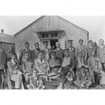 Jack Munroe and his dog sitting with a group of soldiers outside a hospital  building.