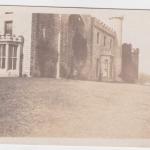 A photograph of a castle in the distance with a soldier posing in front of it.