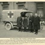 Une photographie en noir et blanc de quatre individus, dont le jeune prince George, posant avec une ambulance motorisée.