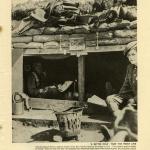 A black-and-white photograph of two soldiers sitting inside a well-constructed dugout in a trench.