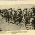 Une photographie en noir et blanc d’une longue file de soldats portant des pioches.