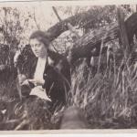 A black-and-white photograph of Mildred Sisler sitting by a wooden fence.