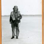 A black-and-white photograph of a soldier in Air Force uniform walking  down a street.